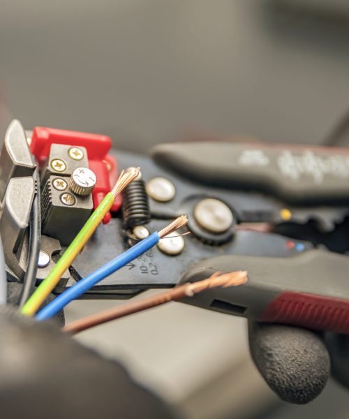Wire strippers. The electrician cleans the protective insulation from the wire using a wire stripper. The process of connecting wires. close-up.